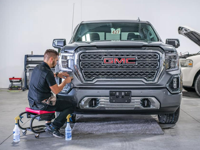 A technician works on the front of a GMC truck